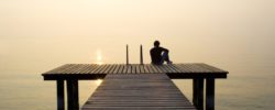 Man sitting on a jetty looking the sunset