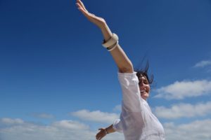 Picture of woman spreading arms wide against open sky