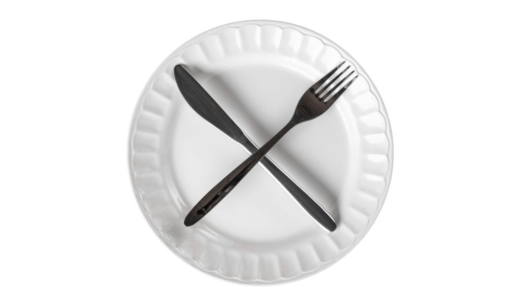 5-day fast concept. Photo of fork and knife crossed on white play