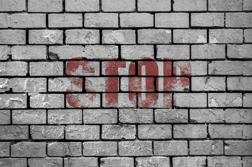 Stop written in red on white brick wall